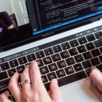 Person coding on a laptop during a video conference, showcasing remote work.